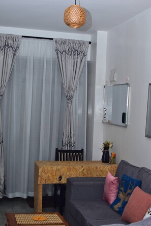 A living room with a sofa, a wooden table, and a mirror on the wall. - The Sunset Nest - Serene 1-bedroom apartment perfect for relaxing stay (Kiambu Province)
