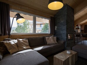 A cozy living room with a sofa, a coffee table, and a fireplace. - Cabin in Turrach With Sauna and Balcony (Stadl-Predlitz)