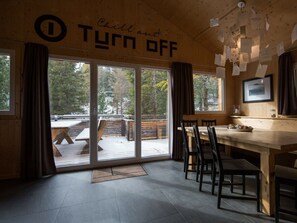 A cozy cabin interior with a large sliding glass door leading to an outdoor deck, a wooden table, and chairs. - Cabin in Turrach With Sauna and Balcony (Stadl-Predlitz)