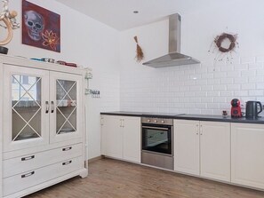 Eine Küche mit weißen Schränken, einem Edelstahlbackofen und einer schwarzen Arbeitsplatte.