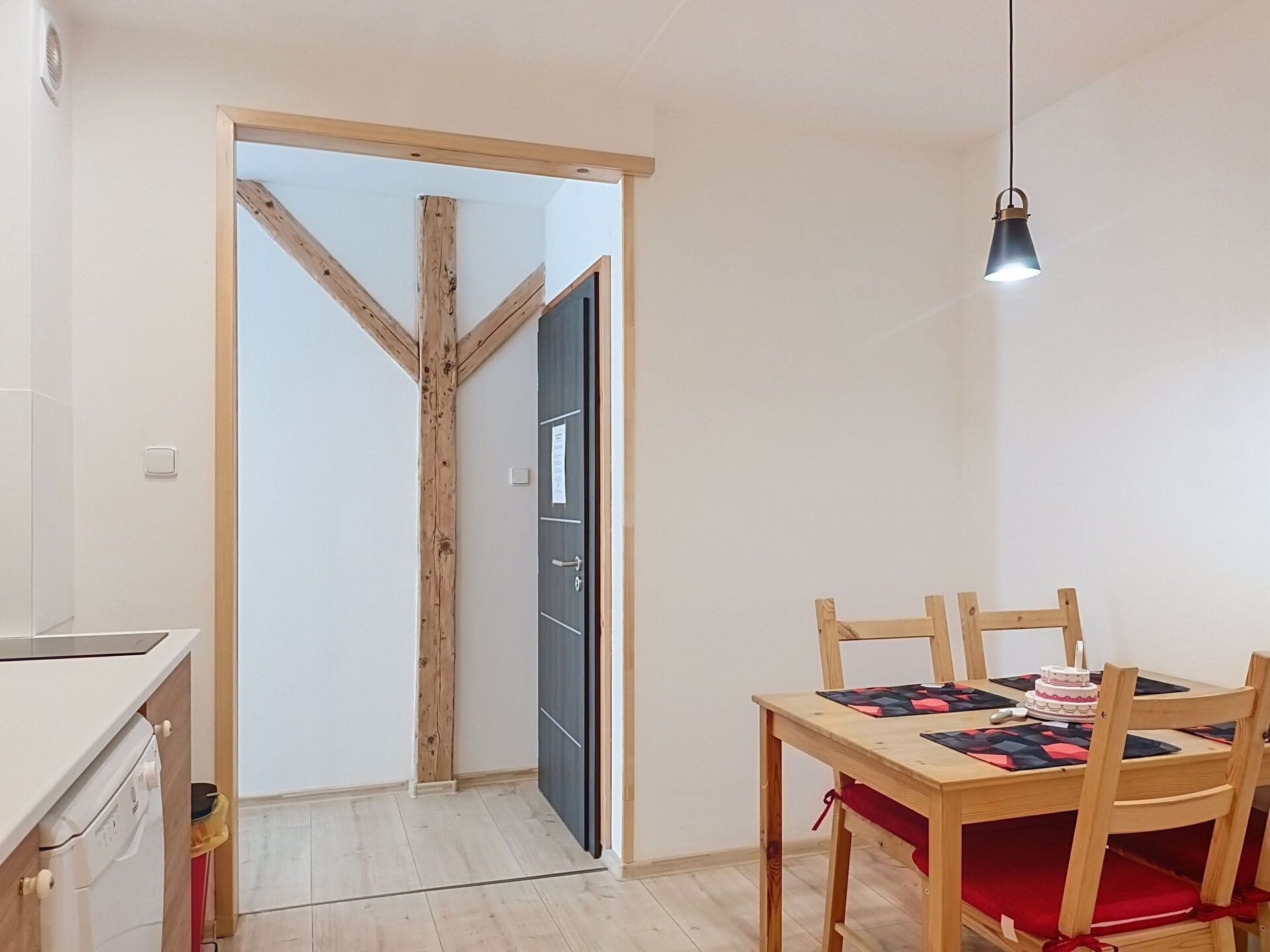 A room with a wooden-framed door, a dining table with chairs, and a pendant light.