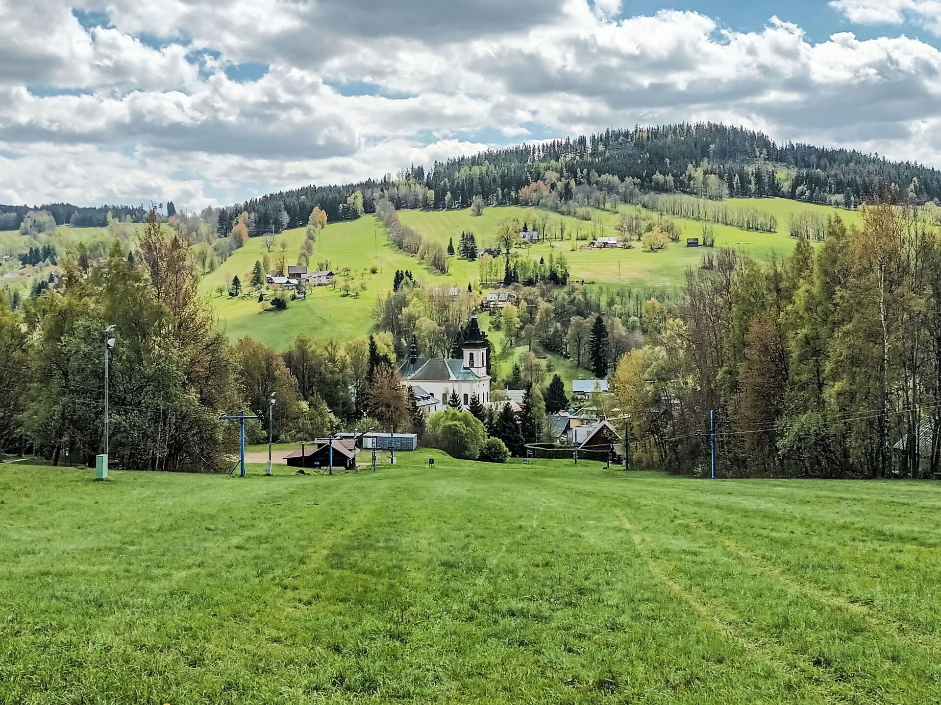 A rural landscape with a church and houses on a hillside.