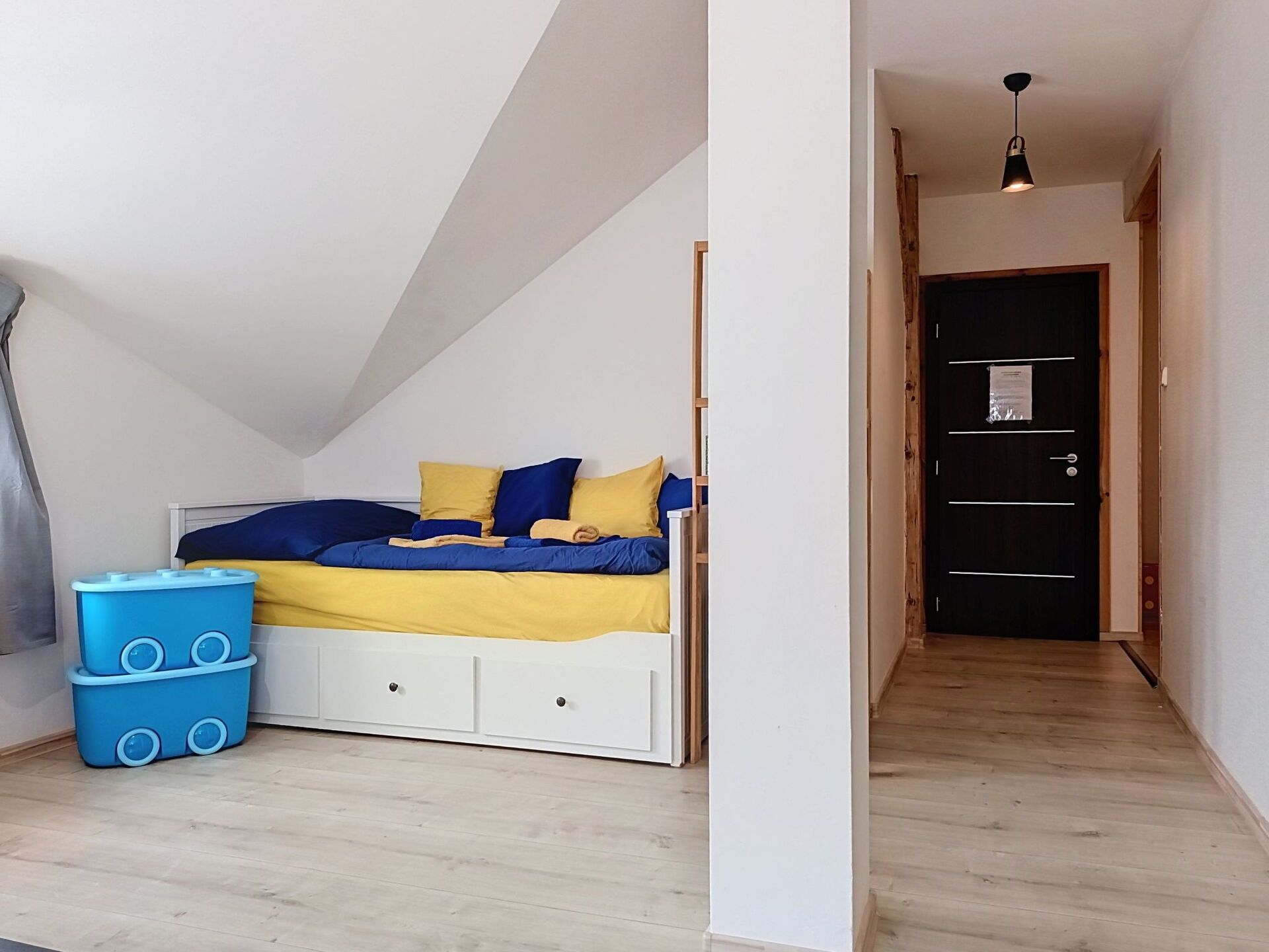 Une chambre avec un lit, un petit meuble de rangement et une porte donnant sur une autre pièce.