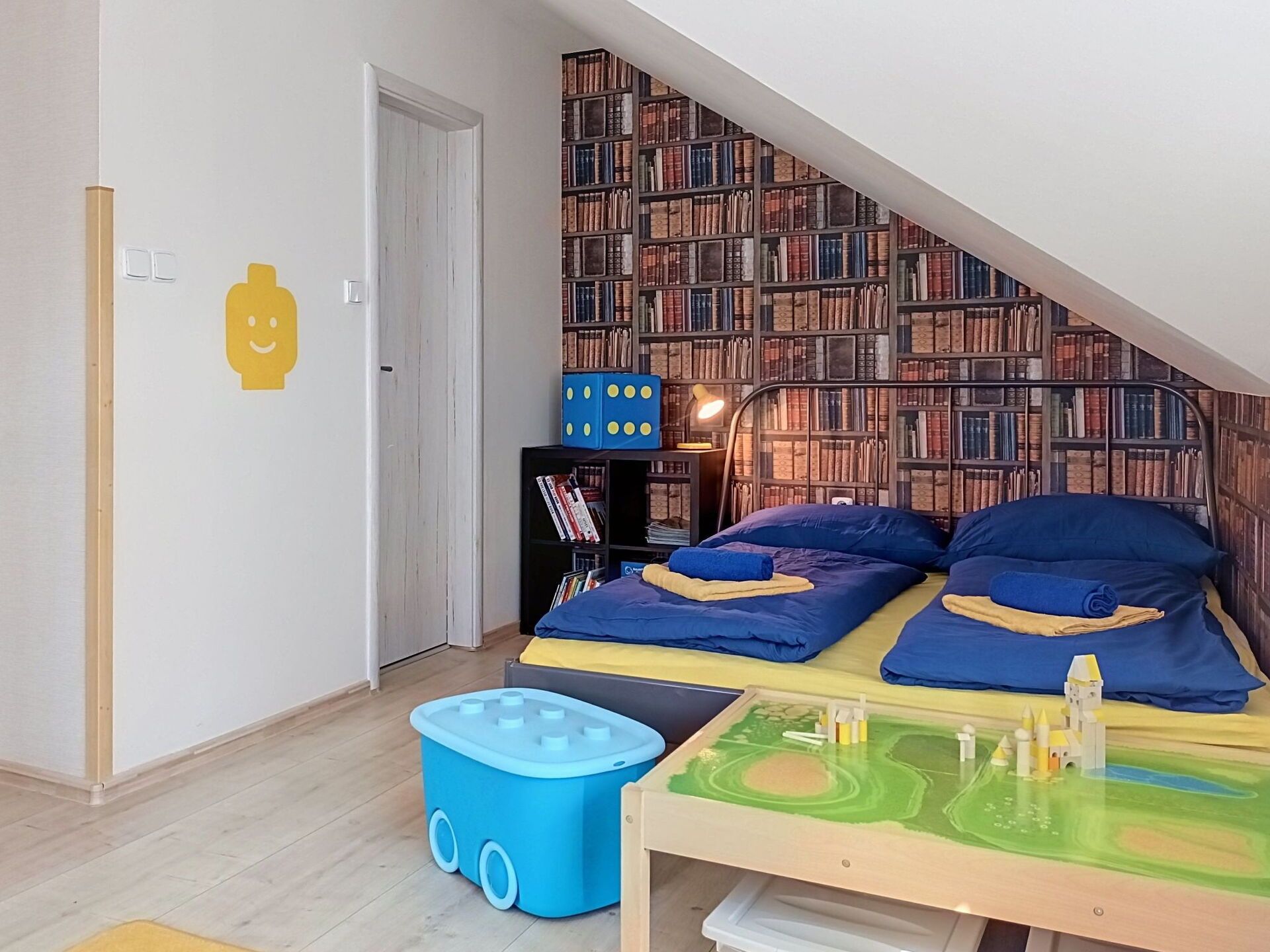 Quarto de criança com cama beliche, estante de livros e espaço para brincar.
