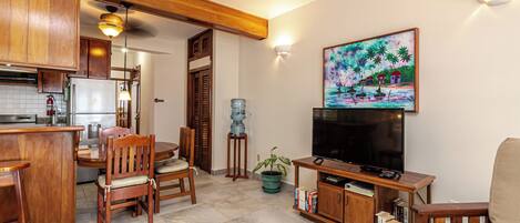 A living room with a television, wooden furniture, a water dispenser, and a painting on the wall.
