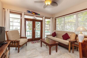 A living room with a sofa, two armchairs, a coffee table, a TV, and a ceiling fan. - Lionfish Suite | Adults-Only Beachfront Escape (San Pedro Town)