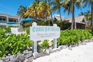 Schild für Coral Bay Villas mit einer Vermietungsstelle am Strand.