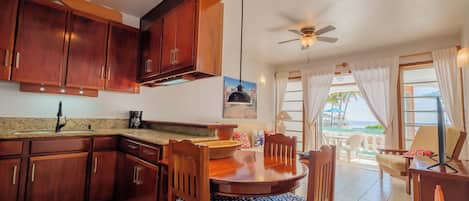 A kitchen with wooden cabinets, a dining table with chairs, and a ceiling fan.