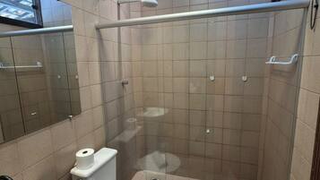 A bathroom with a shower, toilet, sink, and a mirror.