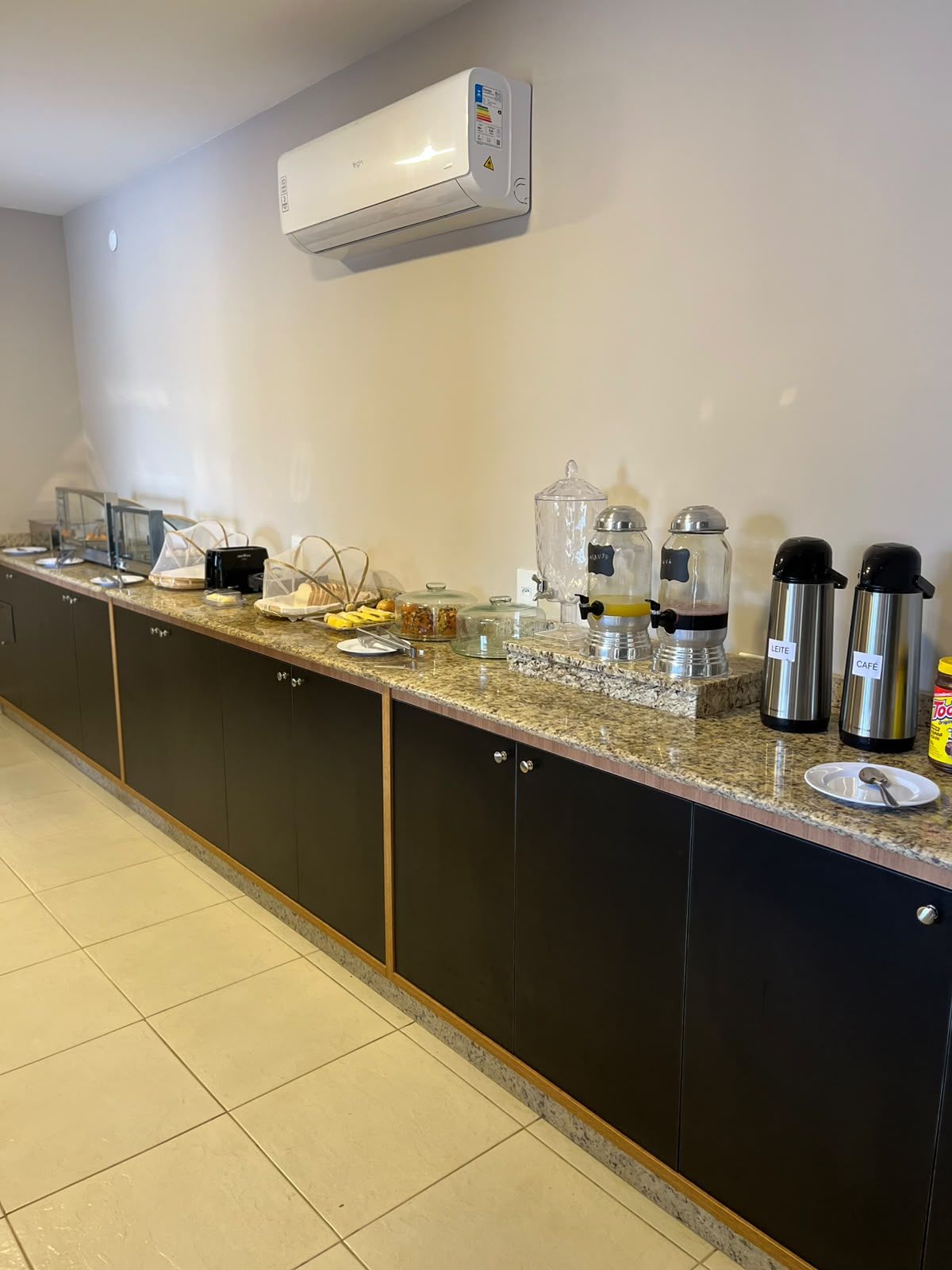 Una cocina con aire acondicionado integrado, encimera de granito y varios electrodomésticos, incluyendo una cafetera y un calentador de alimentos.
