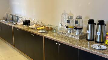 Una cocina con aire acondicionado integrado, encimera de granito y varios electrodomésticos, incluyendo una cafetera y un calentador de alimentos.