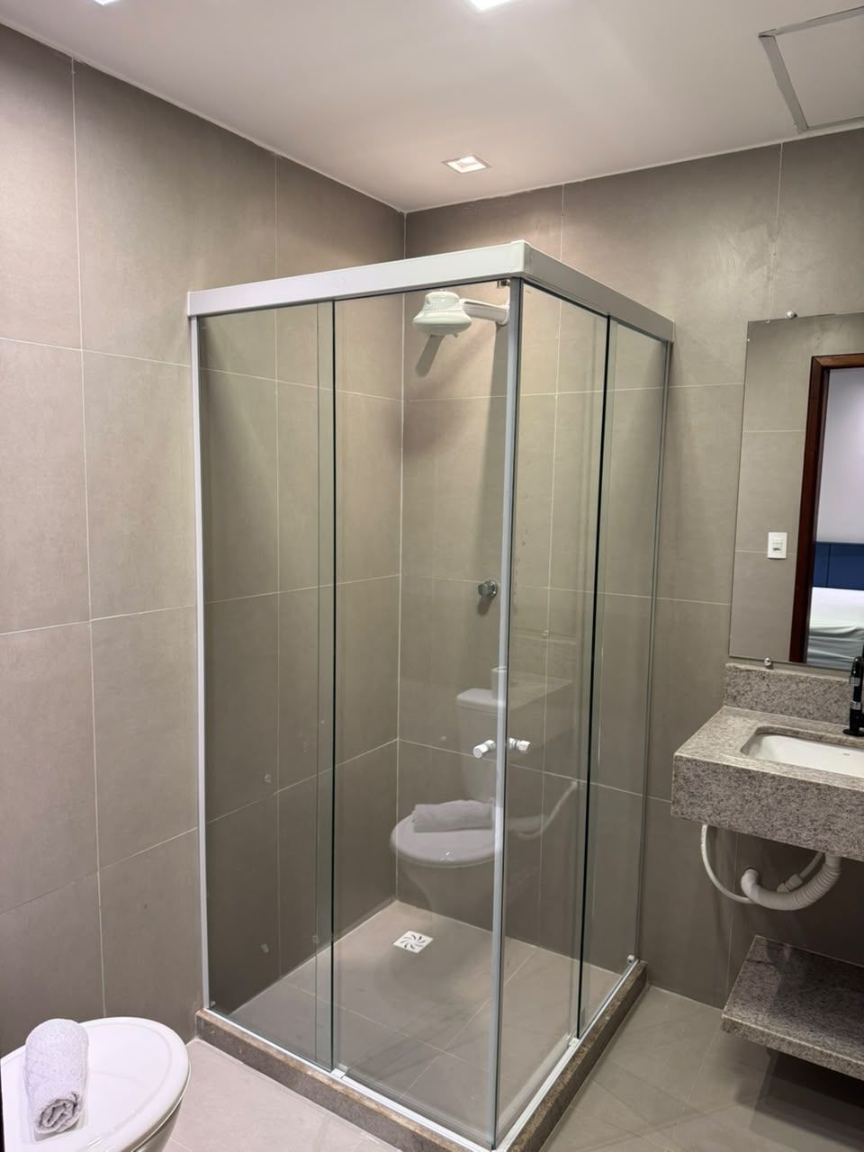 Un baño moderno con ducha de vidrio, inodoro y lavabo con encimera.