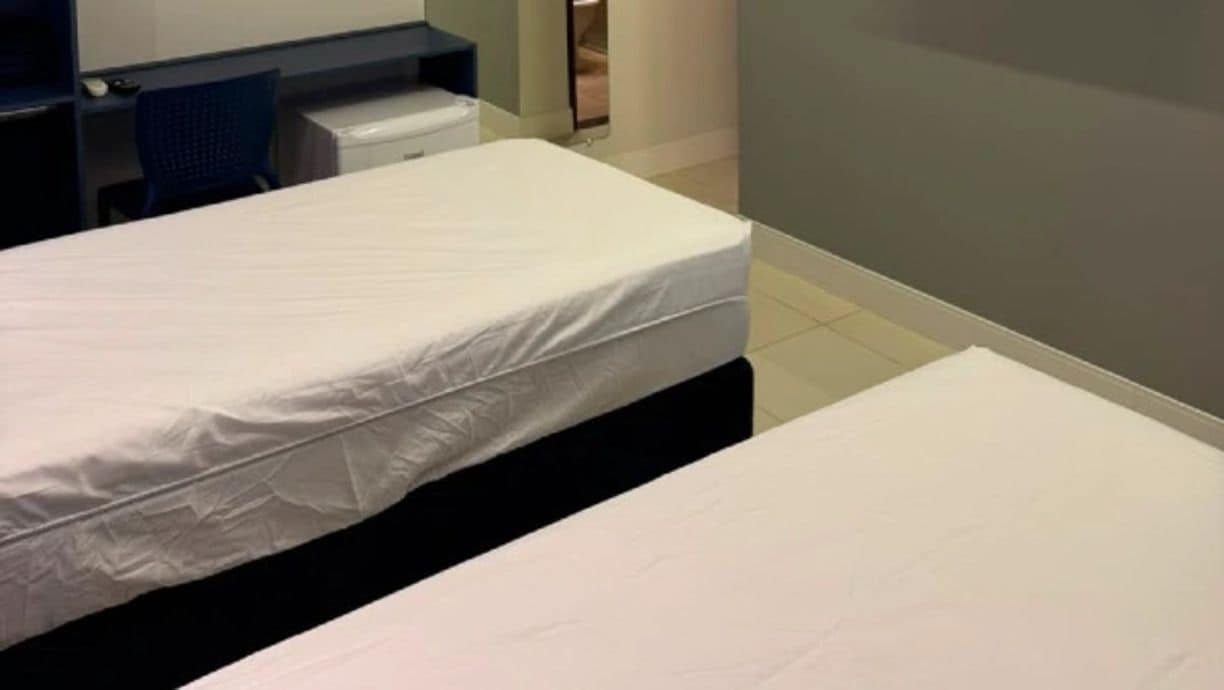 A hotel room with two beds, a desk, and a chair.