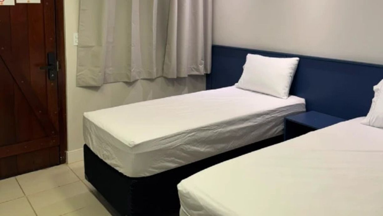A room with two single beds, a wooden door, and a curtain.