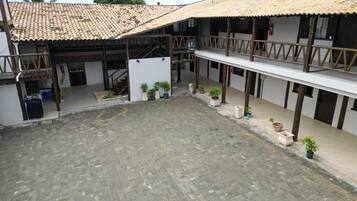 Un patio con techo de tejas, plantas en macetas y una escalera que lleva a un nivel superior.