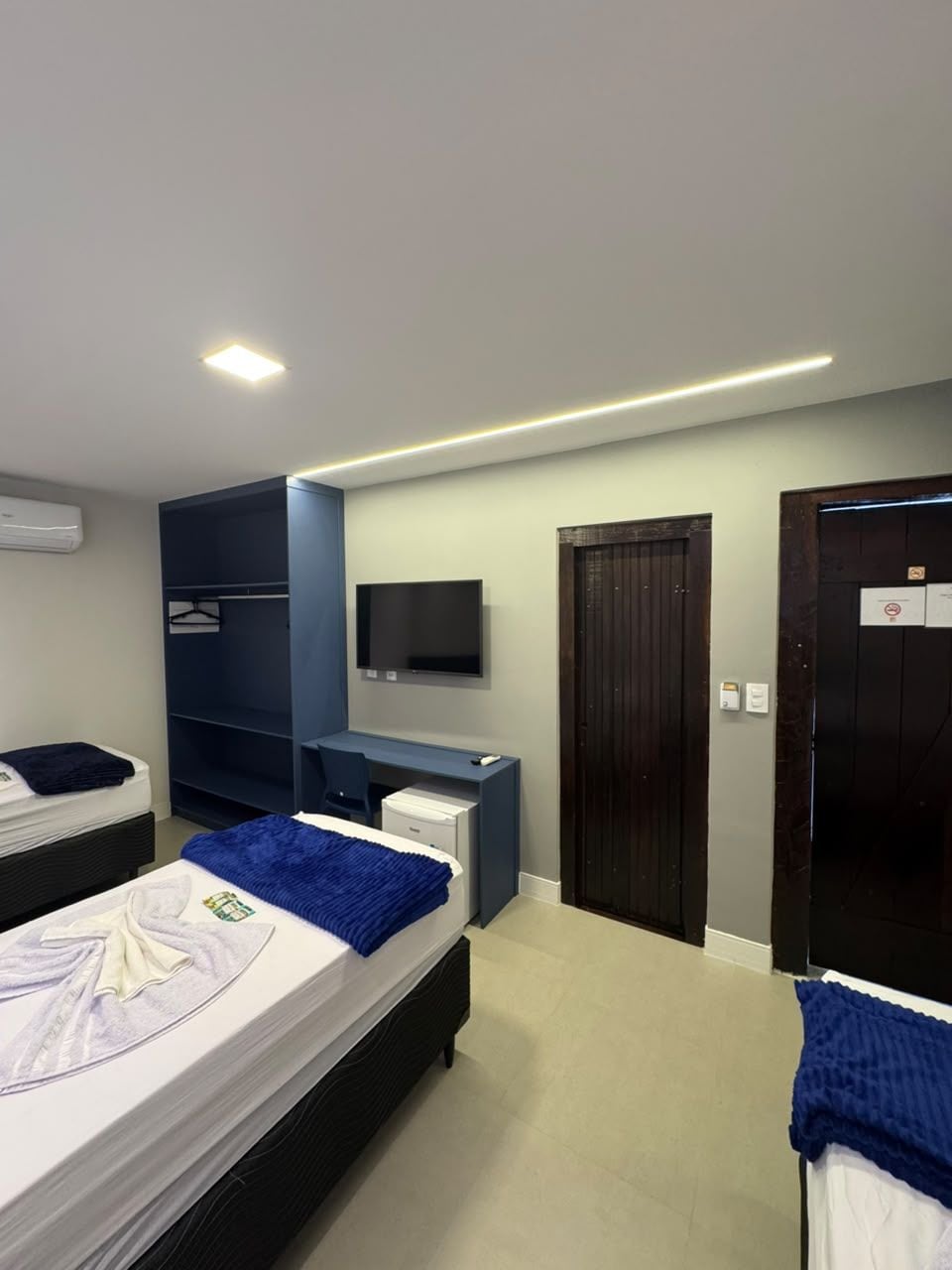 Ein Hotelzimmer mit Bett, Schreibtisch, Kleiderschrank, Fernseher und einer Tür.