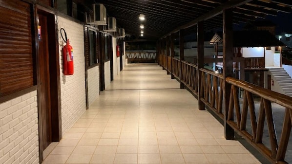 A corridor with tiled flooring, wooden railings, and a fire extinguisher mounted on the wall.