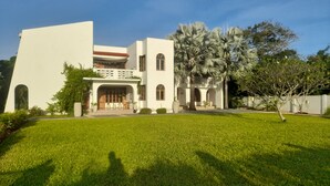 A modern two-story building with a flat roof, a central entrance with a covered porch, and a well-maintained lawn in front. - 3 Bed room Beach Bungalow in Dar es Salaam (Dar es Salaam)