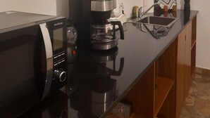 A kitchen with a microwave, coffee maker, and a shelf above the counter. - 3 Bed room Beach Bungalow in Dar es Salaam (Dar es Salaam)