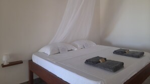 A hotel room with a bed, white linens, a canopy, and two towels. - 3 Bed room Beach Bungalow in Dar es Salaam (Dar es Salaam)