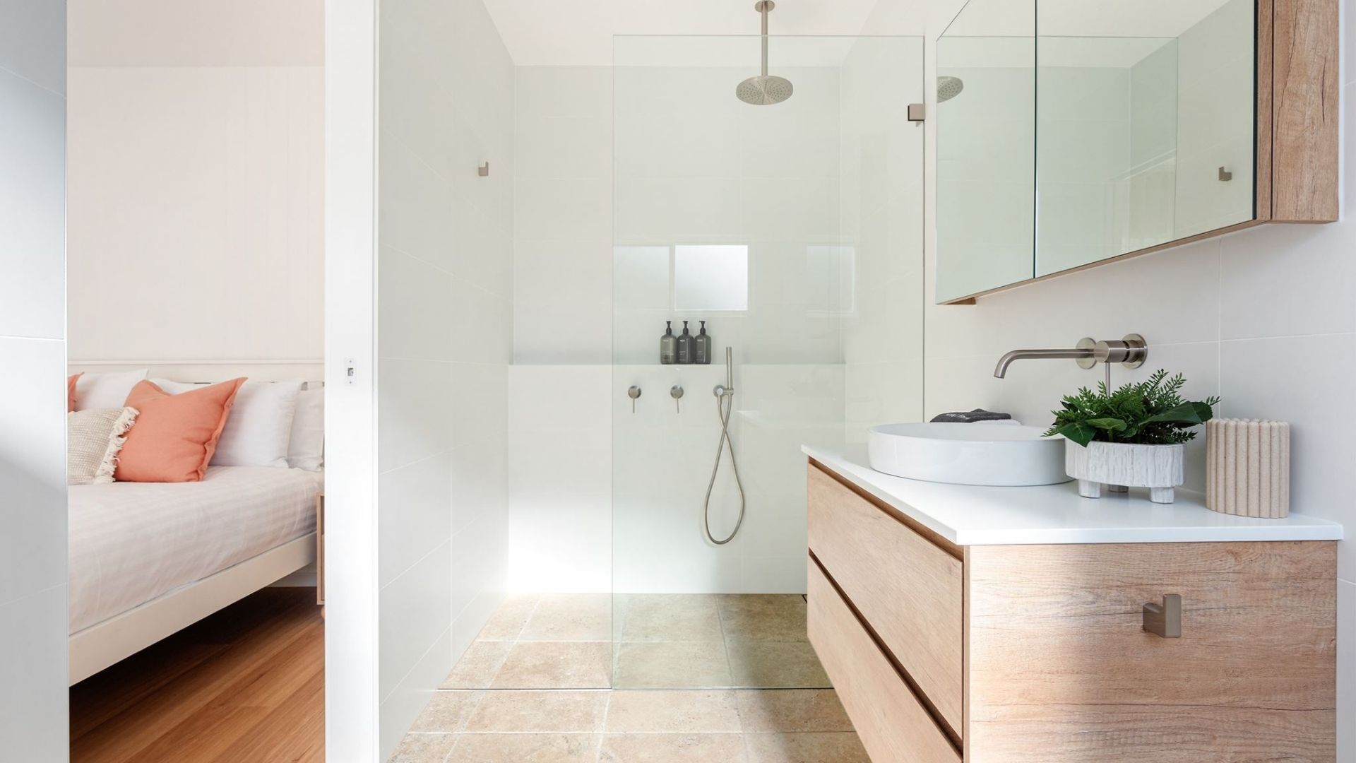 A modern bathroom with a glass shower enclosure, a white sink with a round basin, and a wooden vanity.
