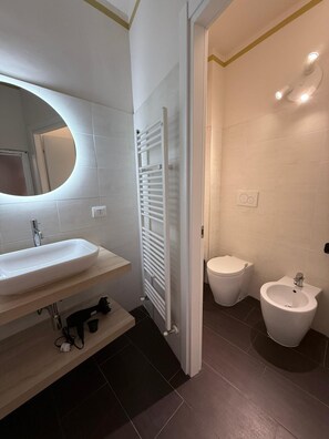 Ein modernes Badezimmer mit einem weißen Waschbecken, einem Spiegel und zwei Bidets.
