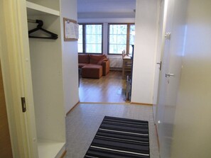 A hallway leading to a living area with a sofa and a radiator. - Karhunvartijan Kartano B2 | 1BR Apt in Ruka Centre (Ruka)
