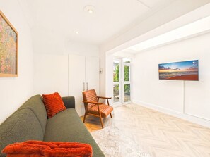 Ein modernes Wohnzimmer mit einer Couch, einem Sessel und einem Gemälde an der Wand.