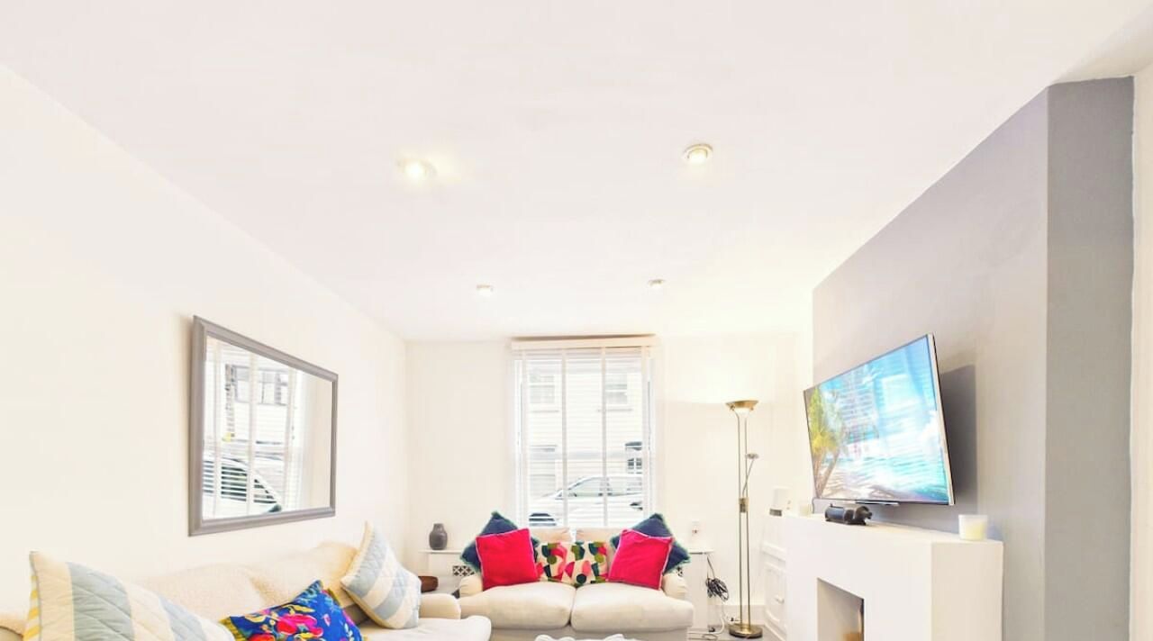 A living room with a sofa, a television, and a window with blinds.
