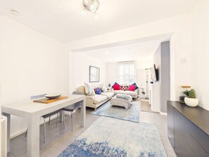 A modern living room with a dining area, a sofa set, and a television. - NEW Duke Street | Modern | Garden | Parking (Gloucestershire)