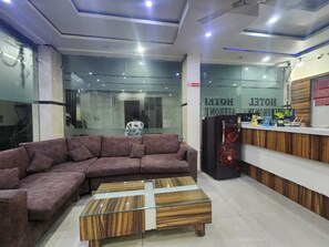 Un moderno vestíbulo de hotel con un sofá modular, una mesa de centro de madera y una recepción.