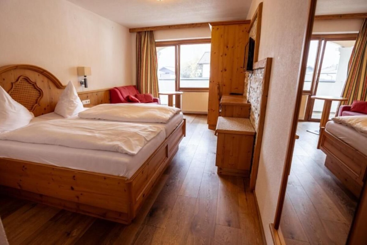 Una habitación de hotel con una cama de madera, un escritorio y una silla.
