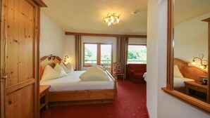 A hotel room with a wooden bed, a red carpet, a balcony, and a large mirror. - Hotel Dax by Alpeffect Hotels (Lofer)