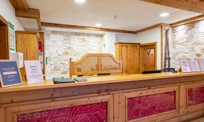 Una recepción con cabecera de madera, pared de piedra de fondo y carteles con información de contacto de emergencia.