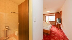 A hotel room with a shower, a bed, a television, and a red carpet. - Hotel Dax by Alpeffect Hotels (Lofer)