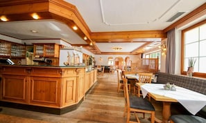 Un restaurante con interiores de madera, una zona de bar y un área de comedor con mesas y sillas.