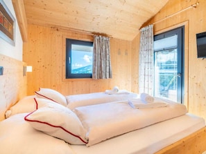 A wooden cabin room with a bed, a window, and a door. - Cabin in Pichl Near Schladming With Sauna (Schladming)