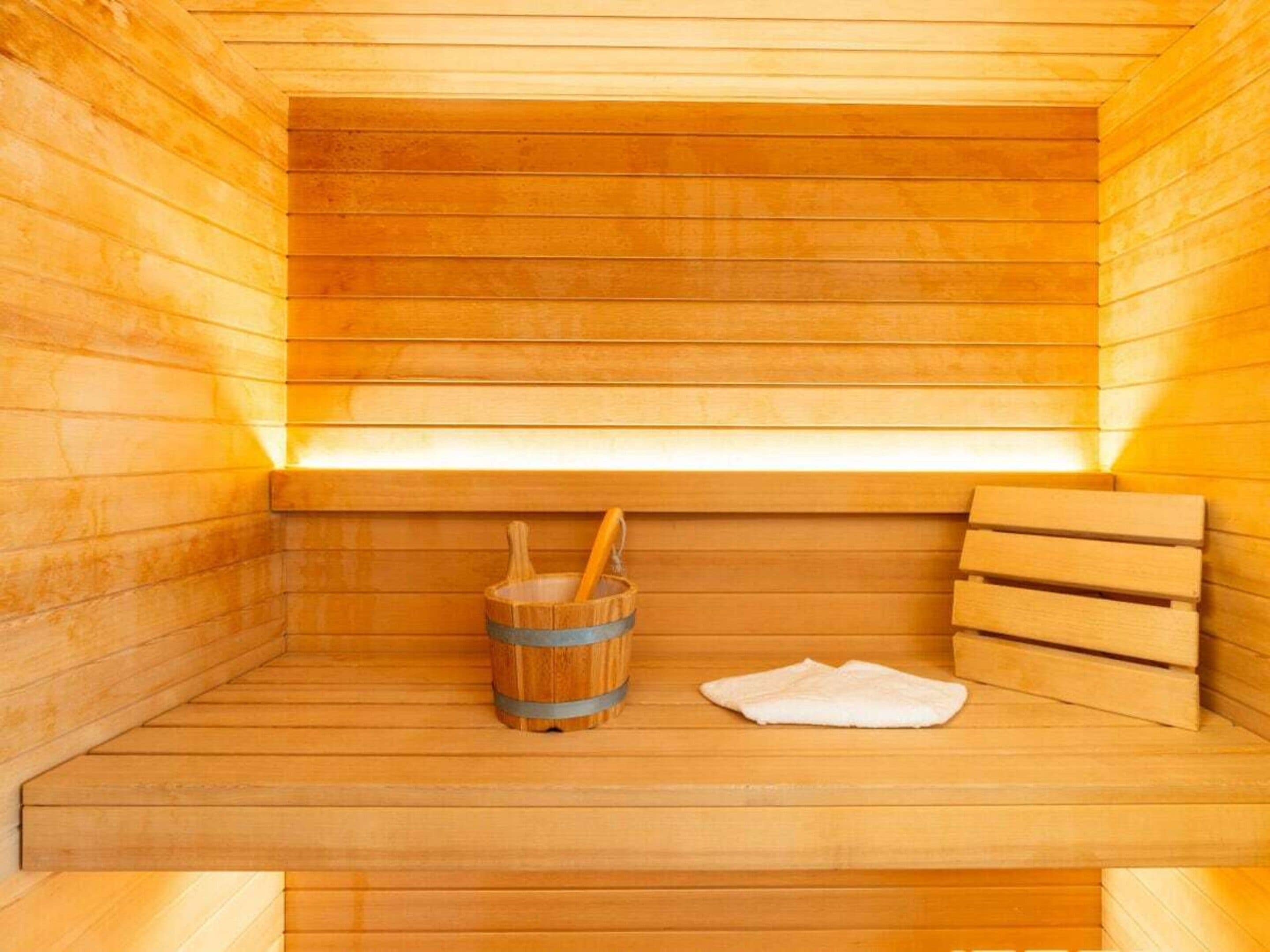 A sauna with wooden benches and a wooden bucket.