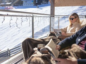 A person reading a magazine in a cozy, fur-lined chair with a snowy landscape view. - Cabin in Pichl Near Schladming With Sauna (Schladming)