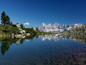 A mountain landscape with a clear lake reflecting the peaks, surrounded by greenery and rocks. - Cabin in Pichl Near Schladming With Sauna (Schladming)