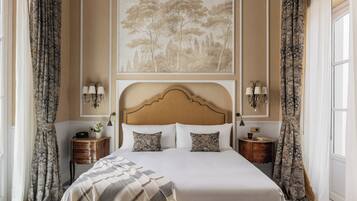 Une chambre d’hôtel avec un grand lit, deux tables de chevet, une tête de lit et un tableau accroché au mur.
