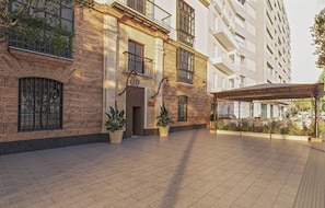 A building with a brick facade, large windows, and a covered outdoor seating area with potted plants. - Casa Alameda 1760 Member Of Melia Collection (Cadiz)