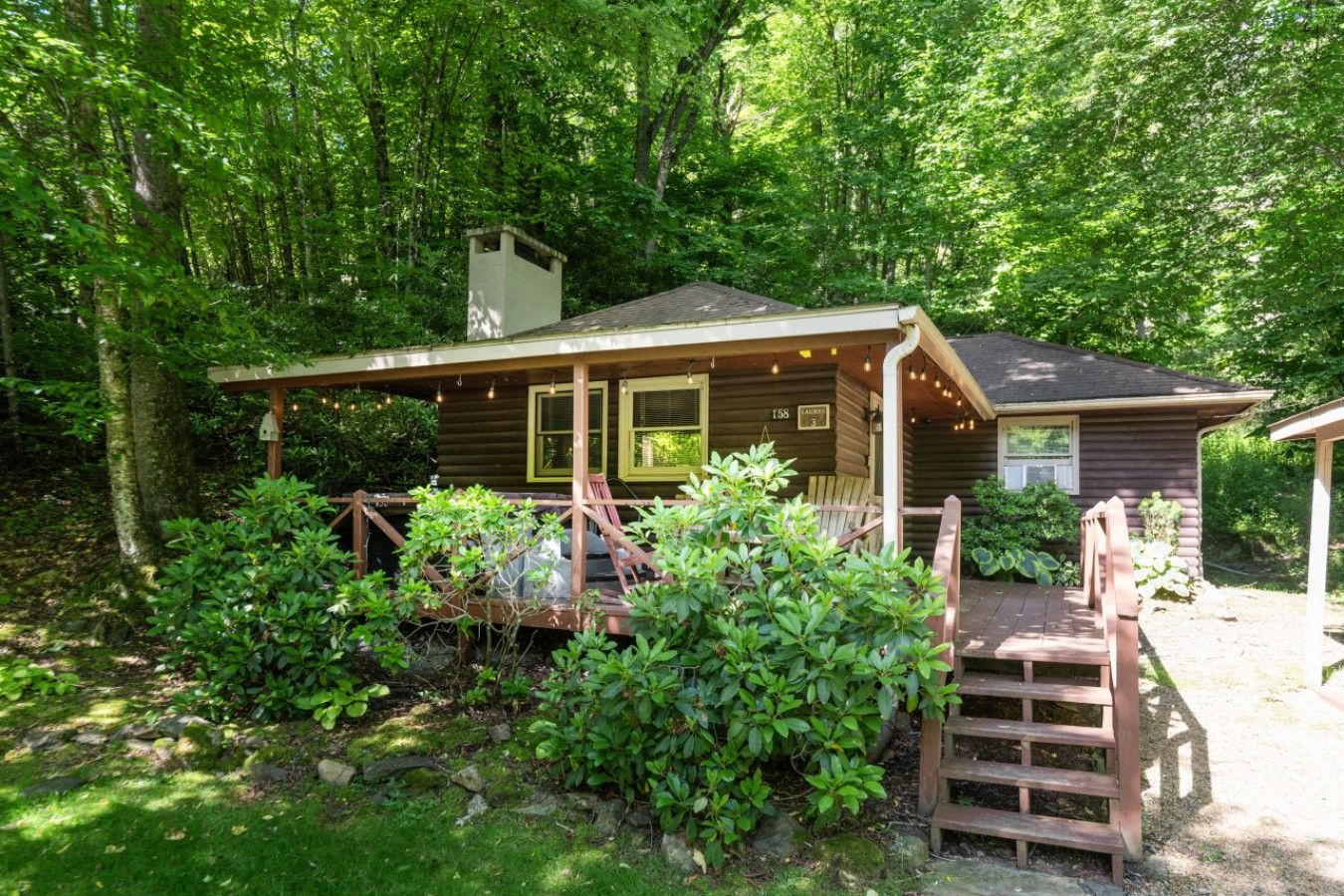 Une cabane dotée d’une véranda, d’un espace salon abrité et d’un petit escalier menant à l’entrée.