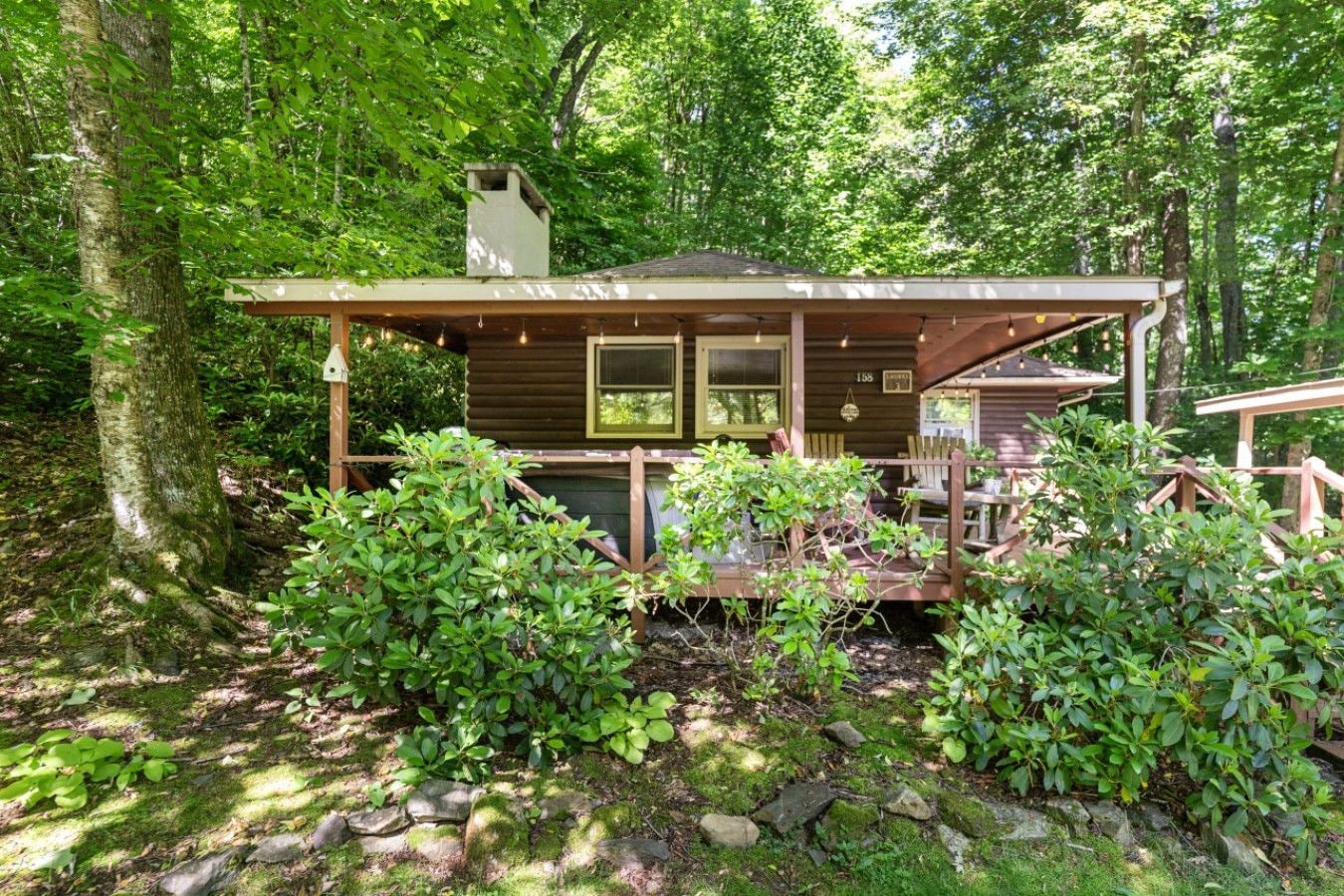 Une cabane dotée d’un porche, entourée d’une forêt dense.