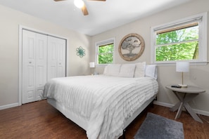 Une chambre à coucher avec un lit, un ventilateur de plafond, une fenêtre donnant sur un beau paysage et une porte.