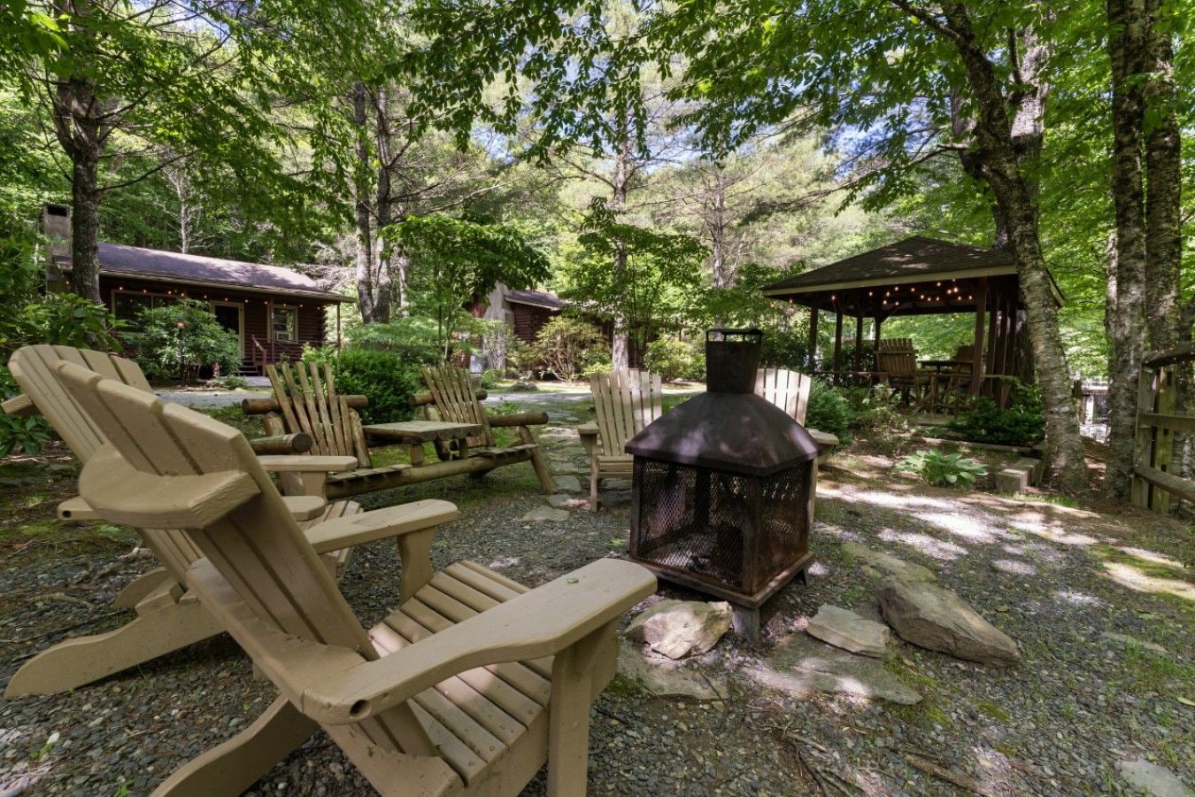 Un espace extérieur boisé, aménagé avec des fauteuils Adirondack, un poêle à bois et des structures en bois.