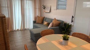 A living room with a sofa, a round table, and a potted plant. - Cozy apartment in Isla Verde (Carolina)