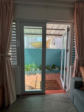 A room with a sliding glass door leading to a balcony with a tiled floor and potted plants. - Cozy apartment in Isla Verde (Carolina)
