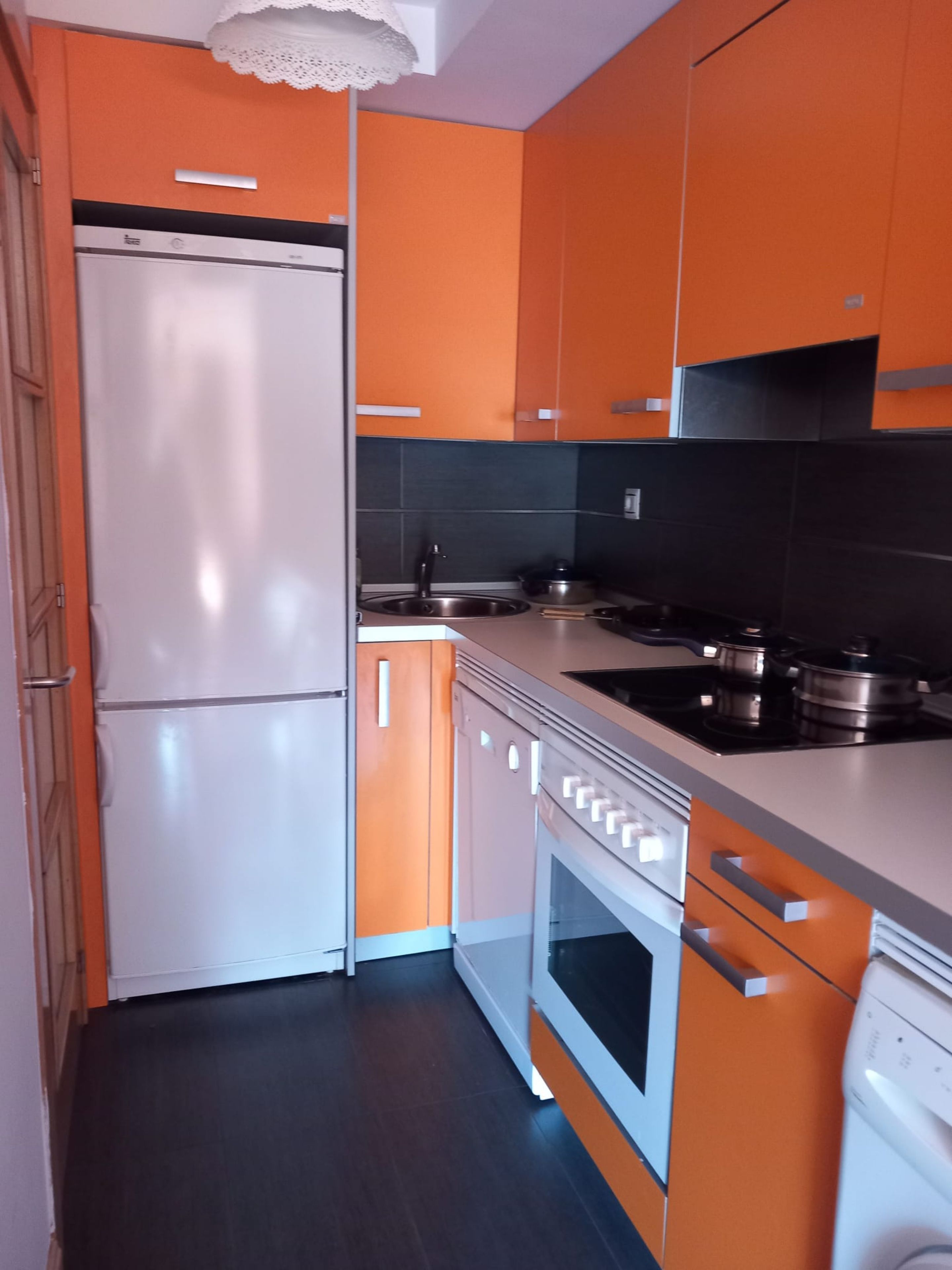 Una cocina compacta con refrigerador, estufa, horno y pileta.