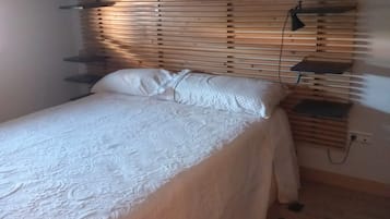 Un dormitorio con cama, detalles de madera en la pared, una mesita de noche y una lámpara.